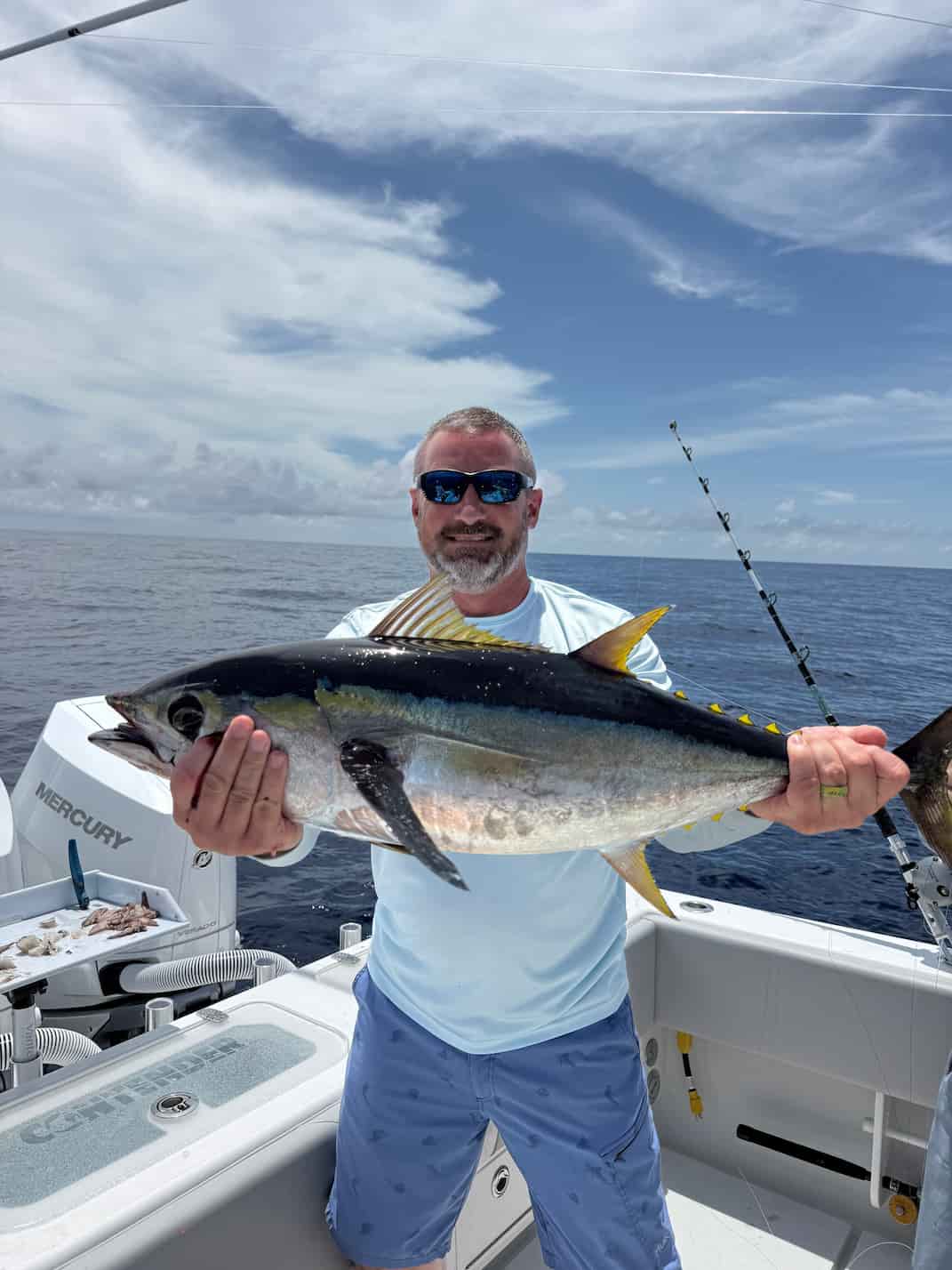 A man on deepblue ocean holding a large blackfin tuna caught on Abacoa Design offshore trolling lures