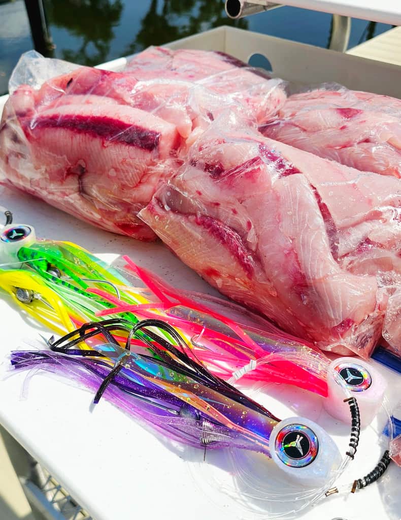 Raw mahi fillets alongside colorful Abacoa Design offshore trolling lures.